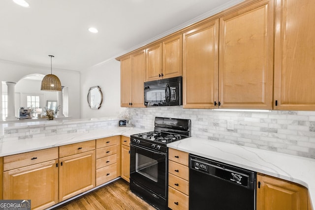 kitchen featuring light stone counters, decorative backsplash, light wood-style flooring, a peninsula, and black appliances