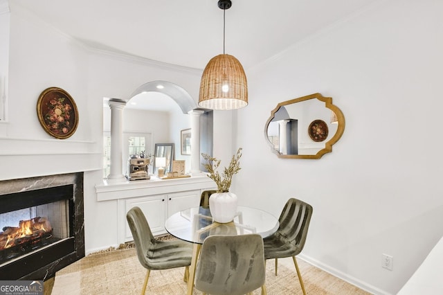 dining room featuring crown molding, decorative columns, baseboards, and a premium fireplace