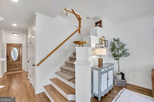 staircase with wood finished floors, baseboards, and ornamental molding