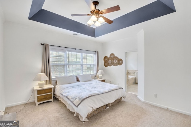 carpeted bedroom with visible vents, baseboards, ensuite bath, a raised ceiling, and a ceiling fan