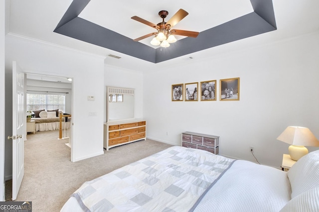 bedroom featuring visible vents, baseboards, a tray ceiling, crown molding, and carpet flooring