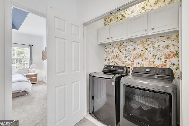 laundry room featuring washing machine and clothes dryer, wallpapered walls, baseboards, light carpet, and cabinet space