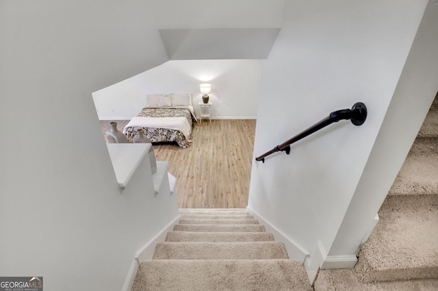 staircase featuring vaulted ceiling, wood finished floors, and baseboards