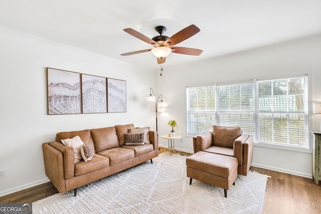 living room with ornamental molding, wood finished floors, baseboards, and ceiling fan