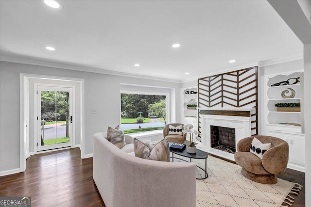 living room with crown molding, built in features, wood finished floors, and a premium fireplace