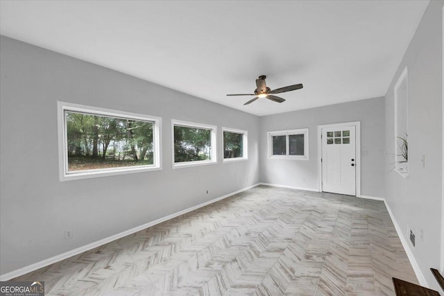 spare room with a ceiling fan and baseboards