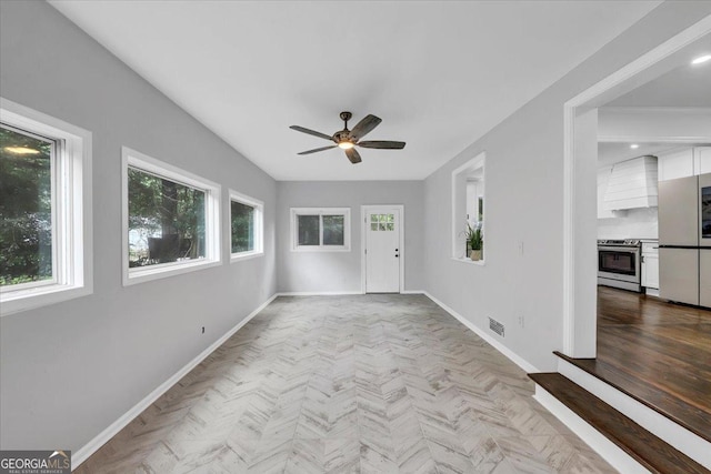 interior space with baseboards, visible vents, and ceiling fan