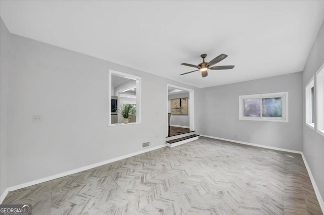 spare room with visible vents, ceiling fan, and baseboards