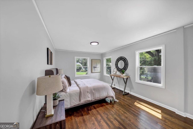 bedroom with crown molding, wood finished floors, and baseboards