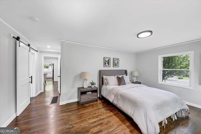 bedroom with wood finished floors, visible vents, baseboards, crown molding, and a barn door