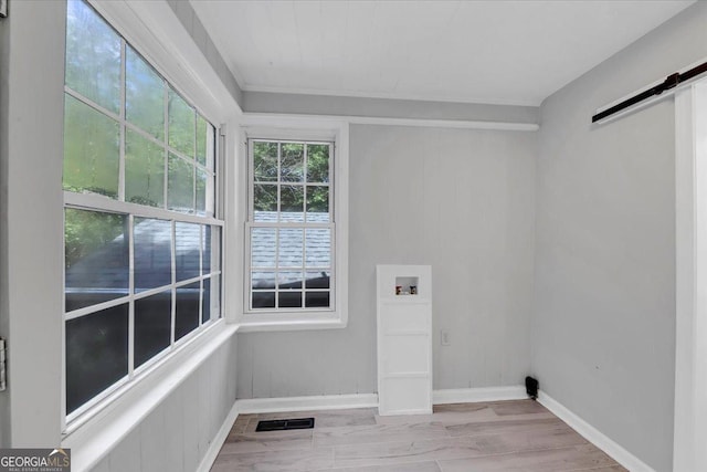 clothes washing area with visible vents, a barn door, washer hookup, laundry area, and wood finished floors