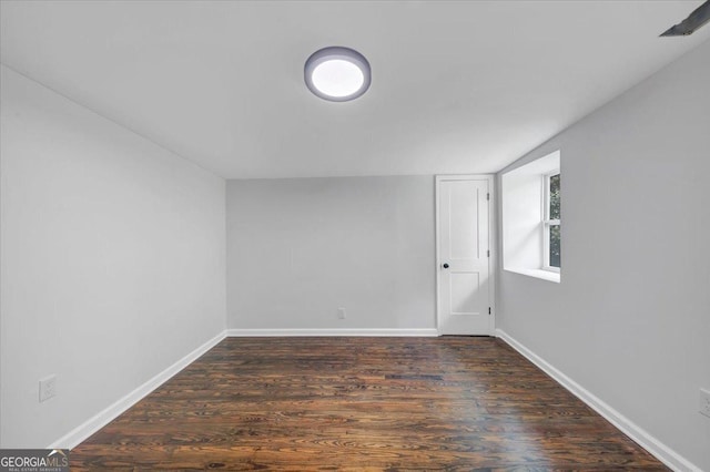 spare room featuring baseboards and dark wood-style flooring