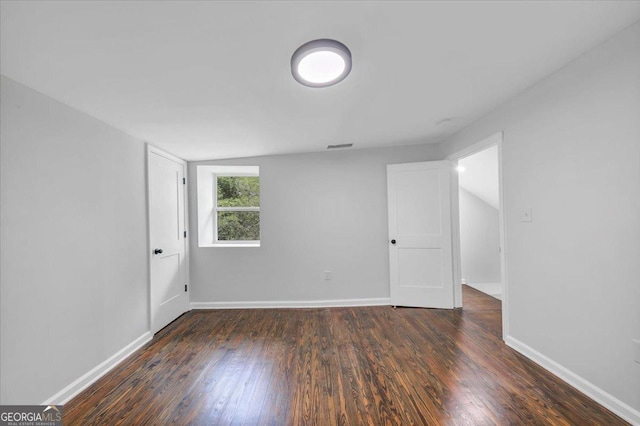 empty room with baseboards, lofted ceiling, and dark wood-style flooring