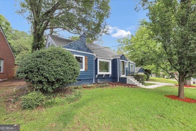 view of front of property with a front lawn, roof with shingles, and a chimney