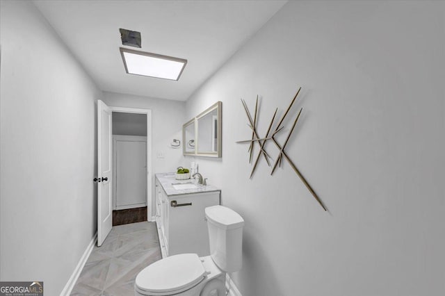 bathroom with vanity, toilet, and baseboards