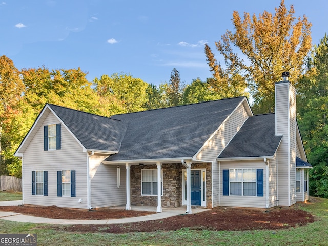 view of front of house with a porch, stone siding, roof with shingles, and a chimney