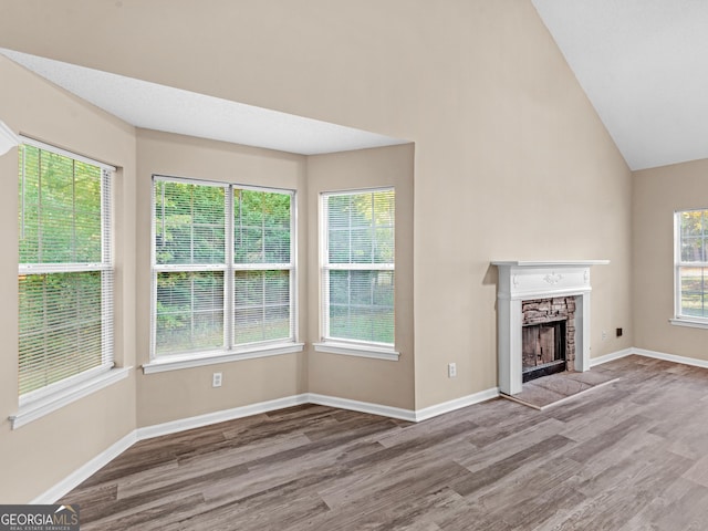 unfurnished living room with baseboards, wood finished floors, and a fireplace with raised hearth