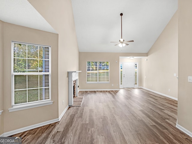 unfurnished living room with baseboards, wood finished floors, and a fireplace with raised hearth