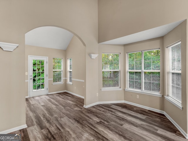 entrance foyer featuring arched walkways, plenty of natural light, baseboards, and dark wood-style flooring