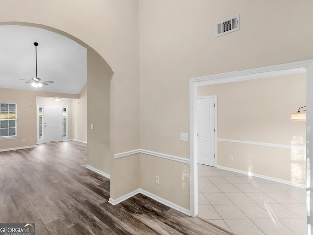 interior space featuring visible vents, baseboards, arched walkways, high vaulted ceiling, and a ceiling fan