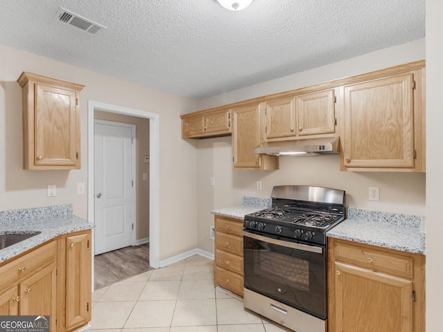 kitchen featuring range with gas stovetop, light stone countertops, visible vents, and under cabinet range hood