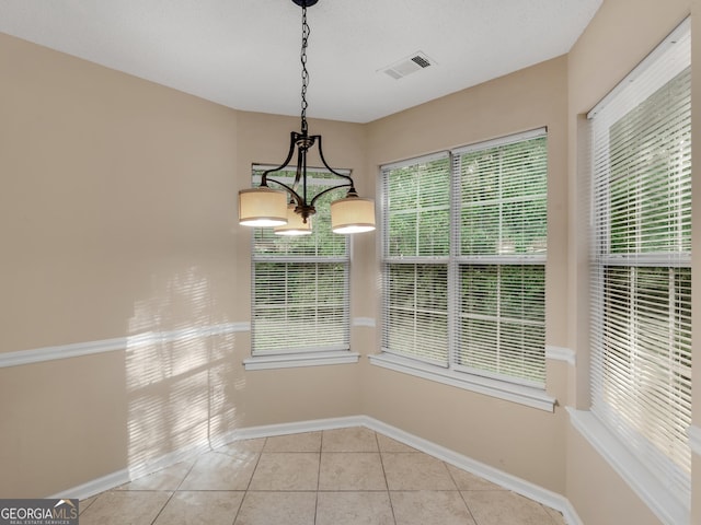 unfurnished dining area featuring light tile patterned floors, visible vents, baseboards, and an inviting chandelier