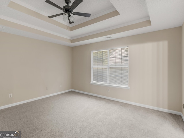 empty room with visible vents, baseboards, crown molding, a raised ceiling, and light colored carpet