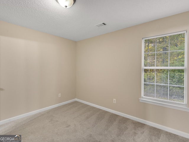 carpeted empty room featuring baseboards, visible vents, and a textured ceiling