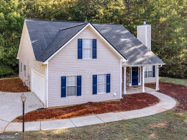 traditional-style house featuring a shingled roof, an attached garage, driveway, and a chimney