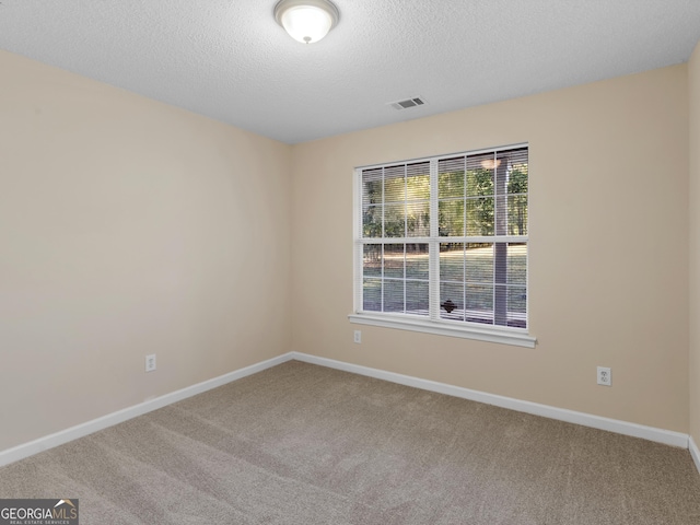 unfurnished room featuring visible vents, baseboards, carpet, and a textured ceiling