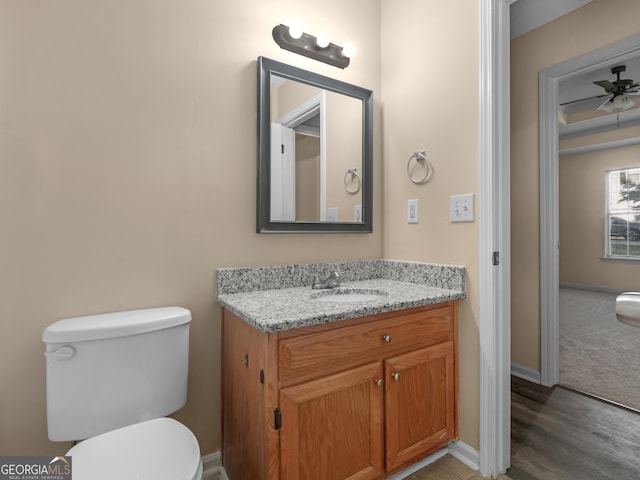 bathroom featuring baseboards, toilet, vanity, and ceiling fan