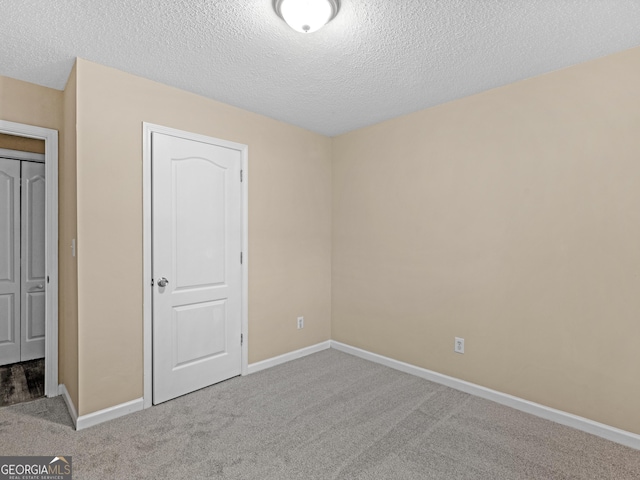 unfurnished bedroom with baseboards, carpet floors, a textured ceiling, and a closet