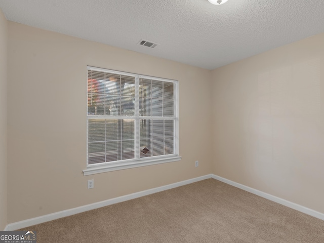 unfurnished room with visible vents, carpet floors, a textured ceiling, and baseboards