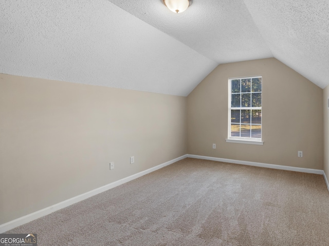 additional living space with lofted ceiling, carpet flooring, baseboards, and a textured ceiling