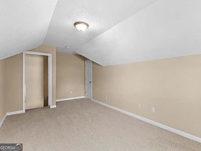 additional living space featuring baseboards, a textured ceiling, carpet flooring, and vaulted ceiling