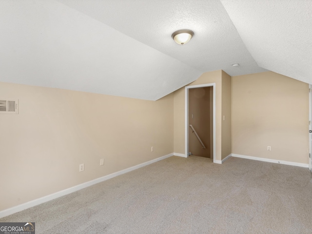 bonus room featuring vaulted ceiling, baseboards, visible vents, and a textured ceiling