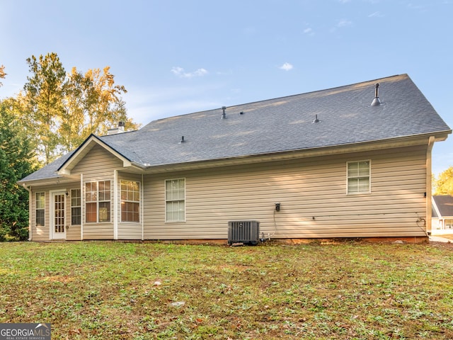 rear view of house with a yard, cooling unit, and roof with shingles