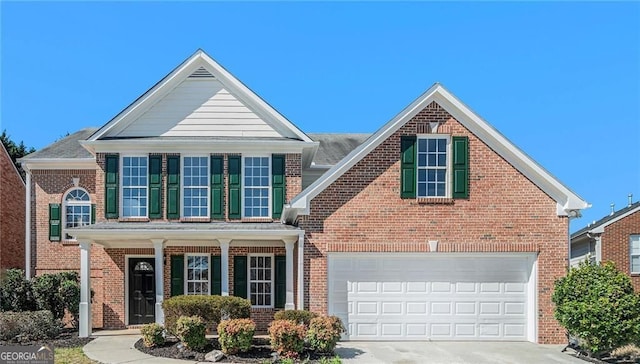 traditional-style home with concrete driveway, a porch, brick siding, and a garage