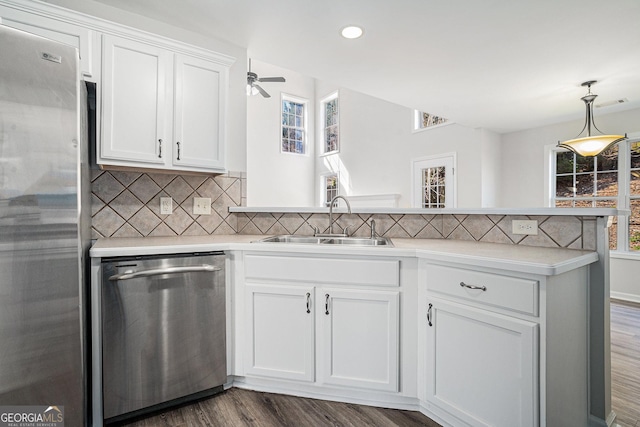 kitchen featuring a sink, plenty of natural light, stainless steel appliances, a peninsula, and light countertops