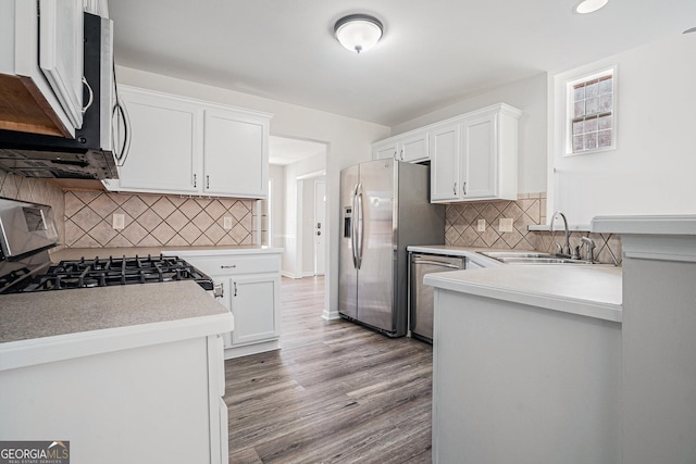 kitchen with light wood finished floors, a sink, stainless steel appliances, white cabinets, and light countertops