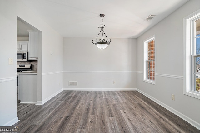 unfurnished dining area with dark wood finished floors, baseboards, and visible vents