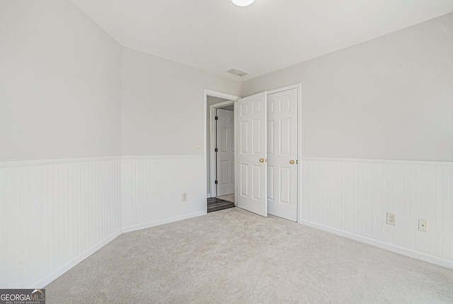 unfurnished bedroom with a closet, carpet floors, and wainscoting