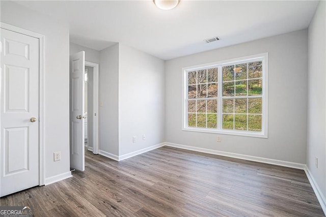 unfurnished bedroom with visible vents, dark wood-style flooring, and baseboards