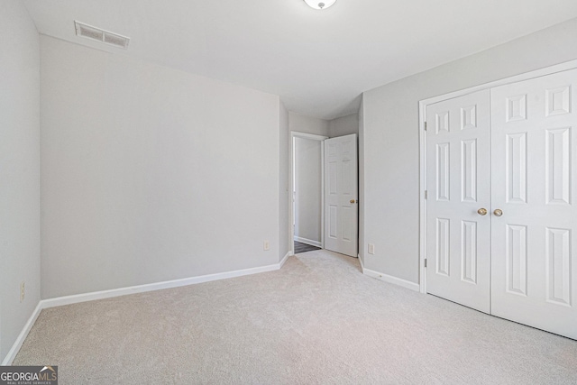 unfurnished bedroom featuring a closet, visible vents, light colored carpet, and baseboards