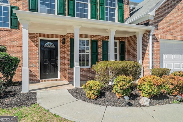 doorway to property featuring brick siding, a garage, and a porch