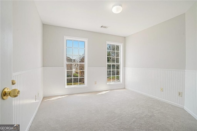 spare room featuring wainscoting, visible vents, and carpet