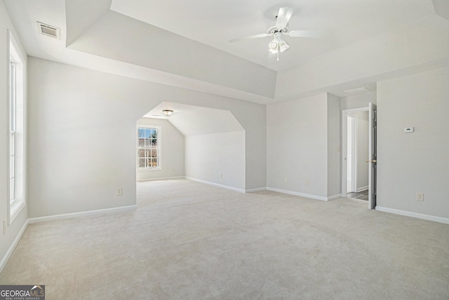 additional living space with a ceiling fan, light colored carpet, visible vents, and baseboards