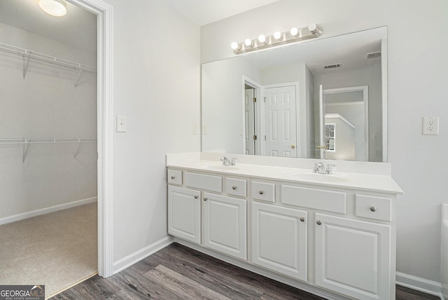 full bath featuring a sink, visible vents, wood finished floors, and double vanity