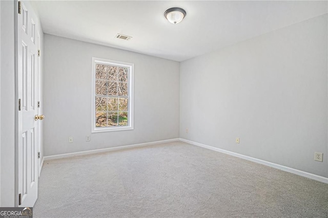 carpeted spare room with visible vents and baseboards