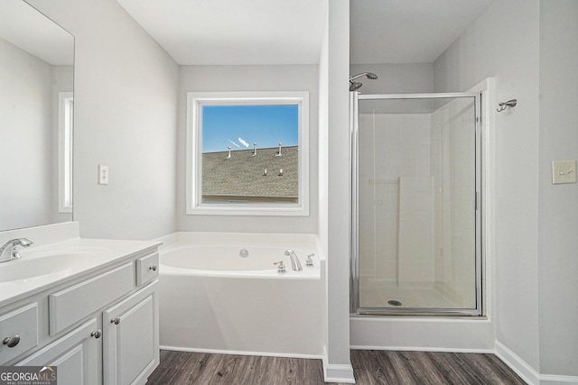 bathroom featuring vanity, wood finished floors, baseboards, a shower stall, and a garden tub